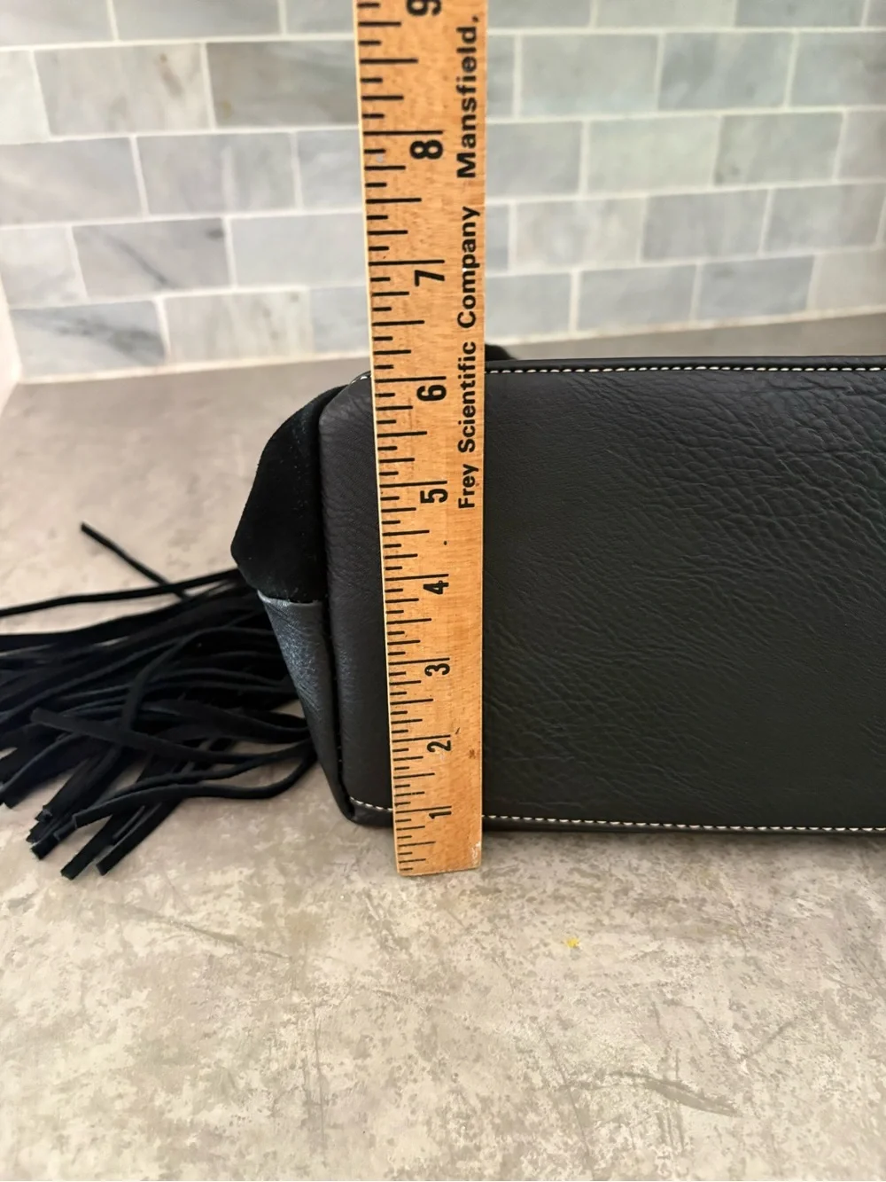 black suede Coco + Carmen hobo bag whipstitching and fringe tassels